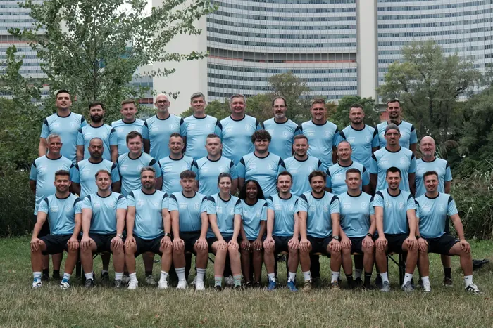 Das Trainer- und Betreuerteam des SV Donau beim Fotoshooting, im Hintergrund die UNO-City